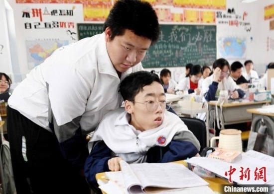 朱金祥(左)把鐘華強(qiáng)放到課堂座位上后，都要把他擺正好，確認(rèn)安全后才回到自己的座位上。 卓忠偉 攝