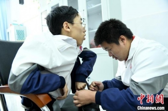 江西省南康中學(xué)北校區(qū)的高三學(xué)生朱金祥(右)正在給鐘華強(qiáng)(左)系好鞋帶。 卓忠偉 攝