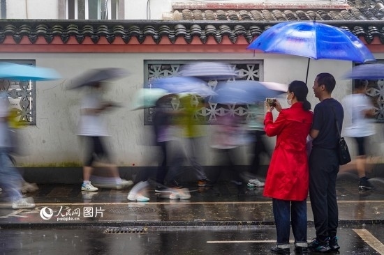 6月7日，在浙江省2023年普通高校招生考試鎮(zhèn)海中學(xué)考點(diǎn)，家長(zhǎng)冒雨目送子女進(jìn)入考場(chǎng)。人民網(wǎng) 章勇濤攝