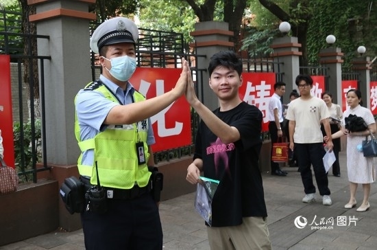 6月7日8時(shí)許，武漢中學(xué)考點(diǎn)門口，交警在維護(hù)秩序，并?？忌鸢耦}名。人民網(wǎng)記者 肖璐欣攝