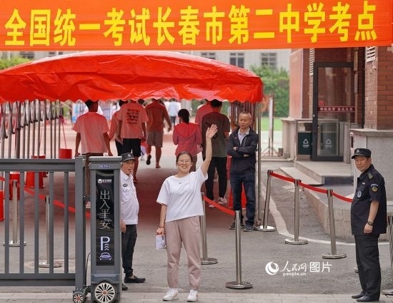 6月7日，在長(zhǎng)春市第二中學(xué)考點(diǎn)，一名考生信心滿滿進(jìn)入考場(chǎng)，并與家長(zhǎng)揮手致意。人民網(wǎng)記者 李洋攝