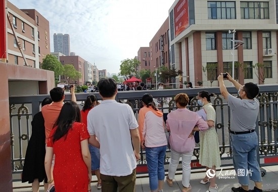 6月7日，武漢市第三中學(xué)考點(diǎn)，考生進(jìn)場(chǎng)后，家長(zhǎng)在柵欄外用手機(jī)拍攝自己的孩子。人民網(wǎng)記者 郭婷婷攝