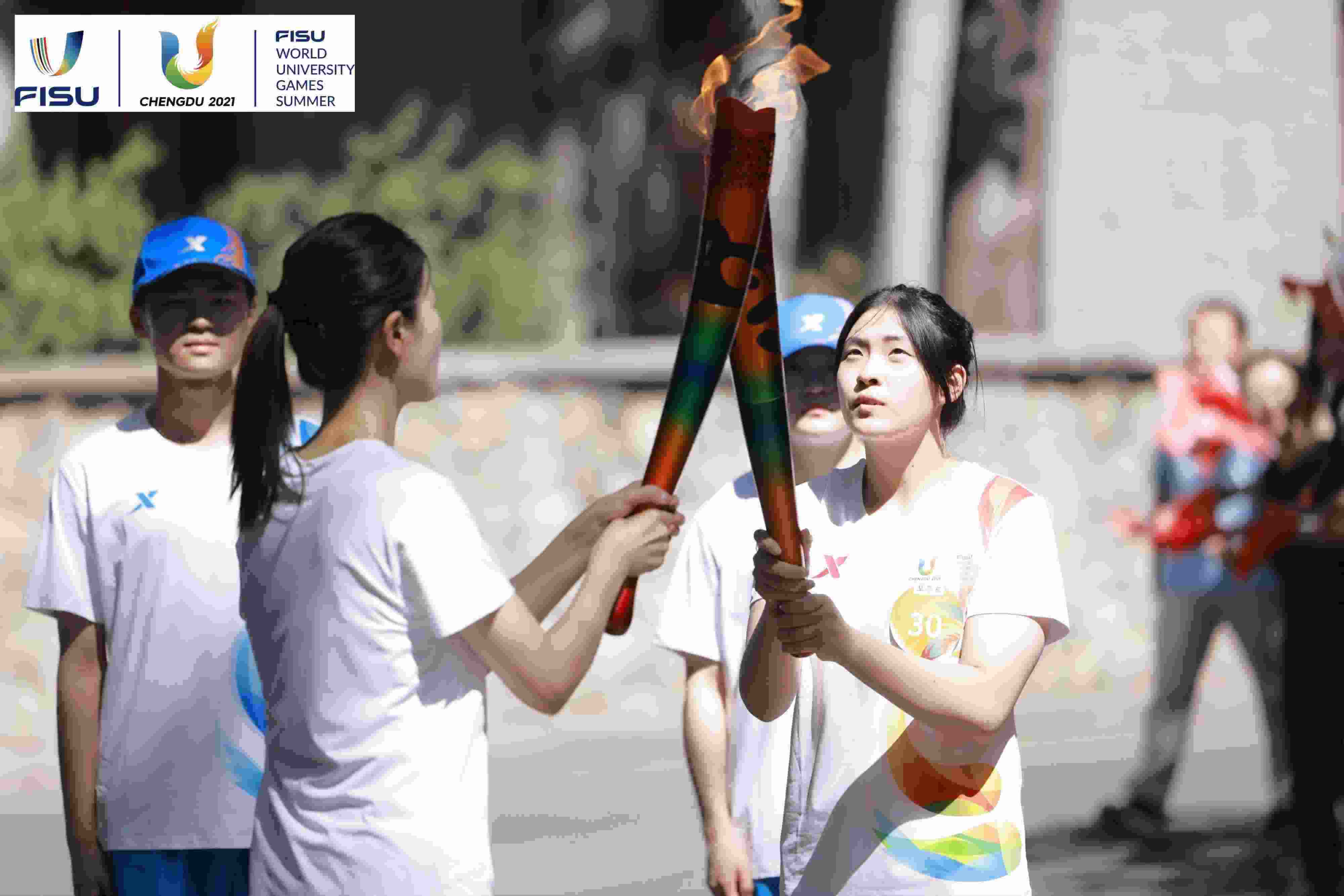 兩名大運(yùn)會(huì)火炬手進(jìn)行火炬?zhèn)鬟f。 圖片來源：成都大運(yùn)會(huì)執(zhí)委會(huì)供圖