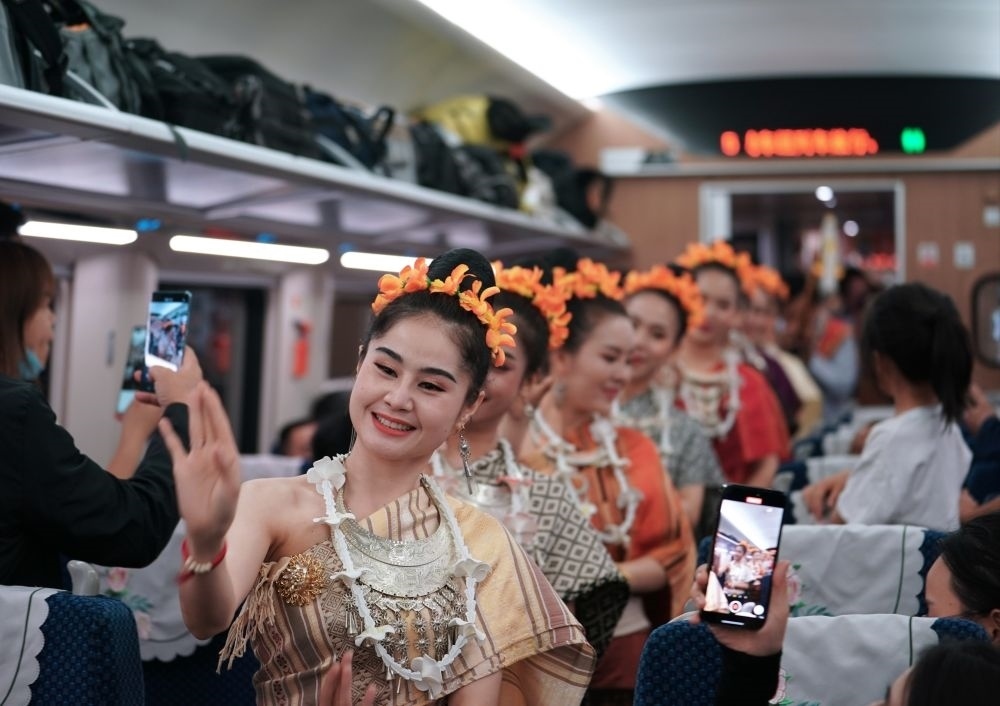 2023年4月13日，老撾工作人員在D887次國(guó)際旅客列車上表演。當(dāng)日，中老鐵路從中國(guó)昆明南站、老撾萬象站雙向?qū)﹂_D887次和D888次國(guó)際旅客列車，兩地乘火車可當(dāng)日通達(dá)。中老鐵路是高質(zhì)量共建“一帶一路”的標(biāo)志性工程。新華社記者 邢廣利 攝