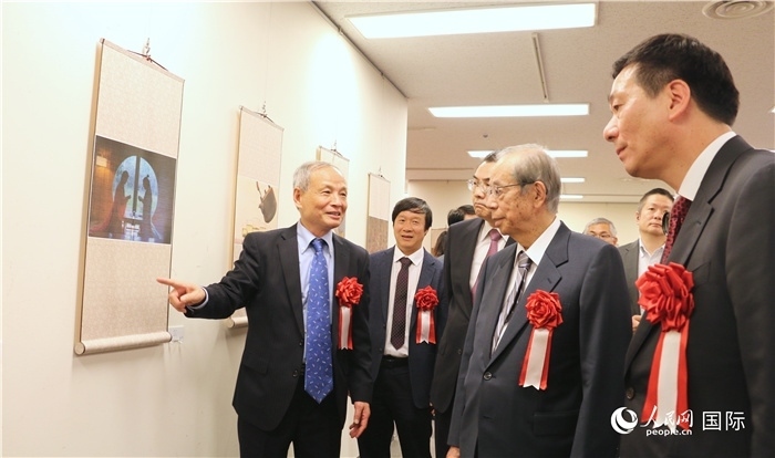 “湖州印象”攝影展主創(chuàng)、世界華人攝影協(xié)會(huì)副會(huì)長(zhǎng)馮學(xué)敏向吳江浩大使、福田康夫前首相等嘉賓介紹展出作品。（人民網(wǎng) 許可攝）