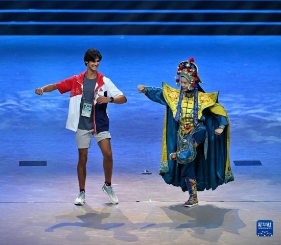 7月29日，美國運動員杜恩（左）在聯(lián)歡會現(xiàn)場與川劇演員互動。新華社記者 蔡湘鑫 攝