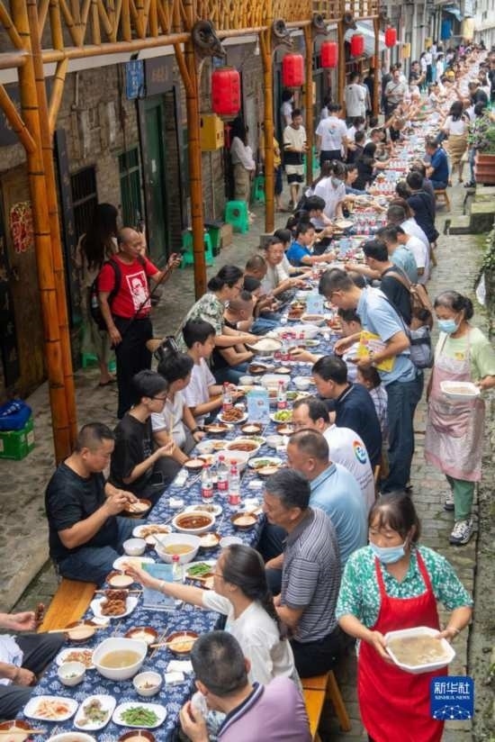7月29日，在重慶市綦江區(qū)安穩(wěn)鎮(zhèn)，人們在“苗家伏羊節(jié)”上吃長桌宴。新華社記者 唐奕 攝