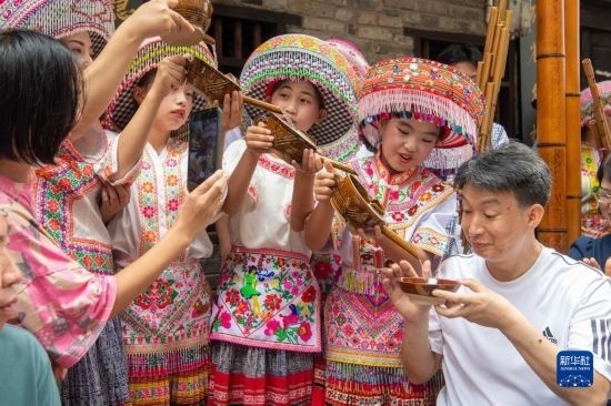 7月29日，在重慶市綦江區(qū)安穩(wěn)鎮(zhèn)，當(dāng)?shù)鼐用裨凇懊缂曳蚬?jié)”上用傳統(tǒng)習(xí)俗向游客表達祝福。新華社記者 唐奕 攝