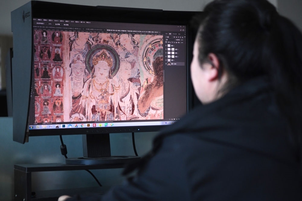 敦煌研究院文物數(shù)字化保護(hù)團(tuán)隊(duì)圖像處理人員年海麗在拼接壁畫圖像（2023年4月25日攝）。數(shù)字化探索為莫高窟的保護(hù)與傳承開辟了全新路徑，數(shù)字技術(shù)讓敦煌文物走出洞窟，跨出國門，走向“永久保存、永續(xù)利用”。新華社記者 陳斌 攝