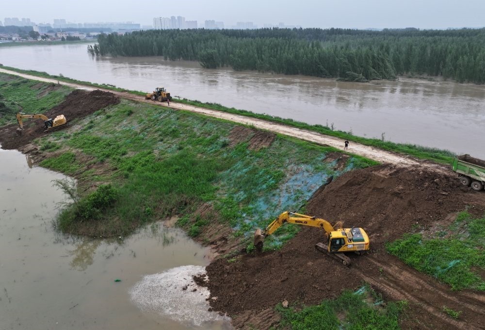 工人操作機械在白溝河左堤白溝新城高橋村段進行除險加固作業(yè)（8月4日攝，無人機照片）。新華社記者 朱旭東 攝