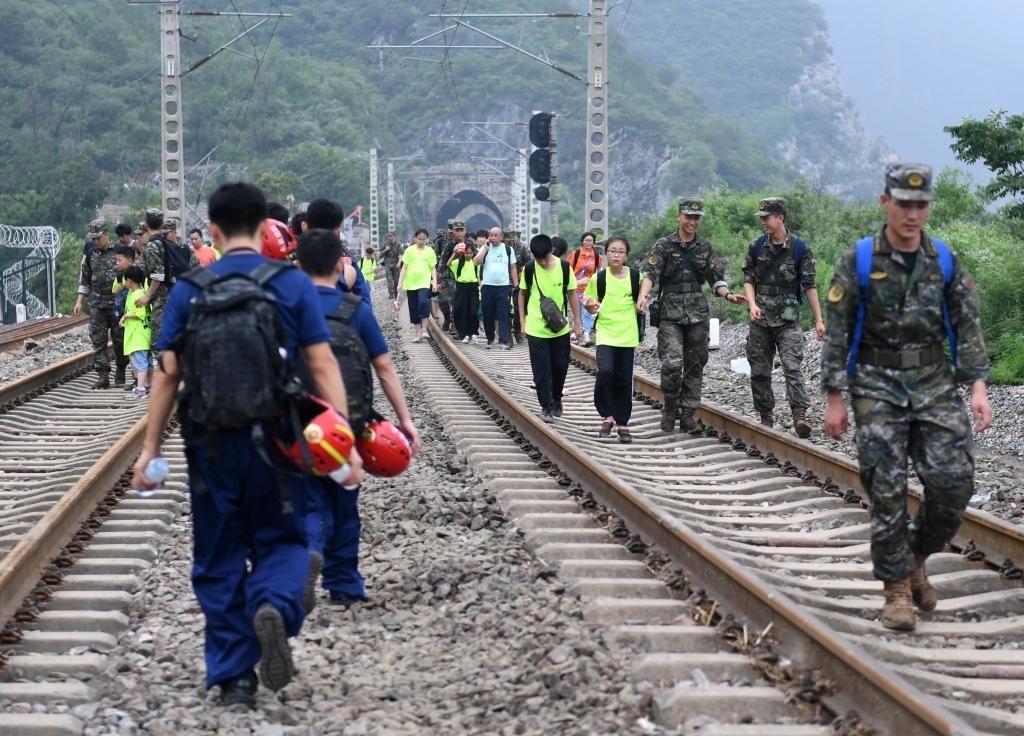 8月2日，部分滯留在北京市門頭溝山區(qū)受困列車的旅客，在救援人員幫助下前往轉(zhuǎn)運(yùn)客車。新華社記者張晨霖 攝