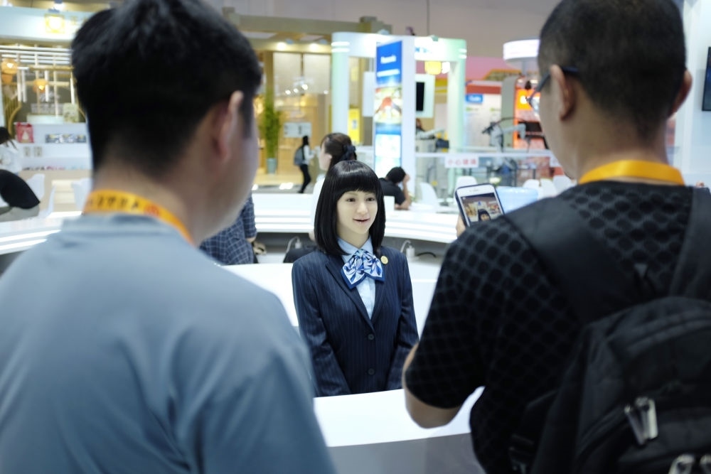 9月1日，媒體記者在國家會(huì)議中心與服務(wù)機(jī)器人互動(dòng)。新華社記者 劉夢(mèng)琪 攝