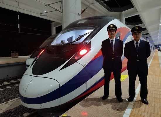 劉銀能（右一）與中國師父鄔俊鴻在動車組前合影。受訪者供圖