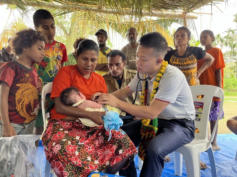 2023年8月5日，在巴布亞新幾內(nèi)亞中央省的一個(gè)村莊里，第12批援巴新中國醫(yī)療隊(duì)副隊(duì)長、新生兒科副主任醫(yī)師劉振球?yàn)楫?dāng)?shù)貗雰郝犜\檢查。新華社發(fā)（第12批援巴新中國醫(yī)療隊(duì)供圖）