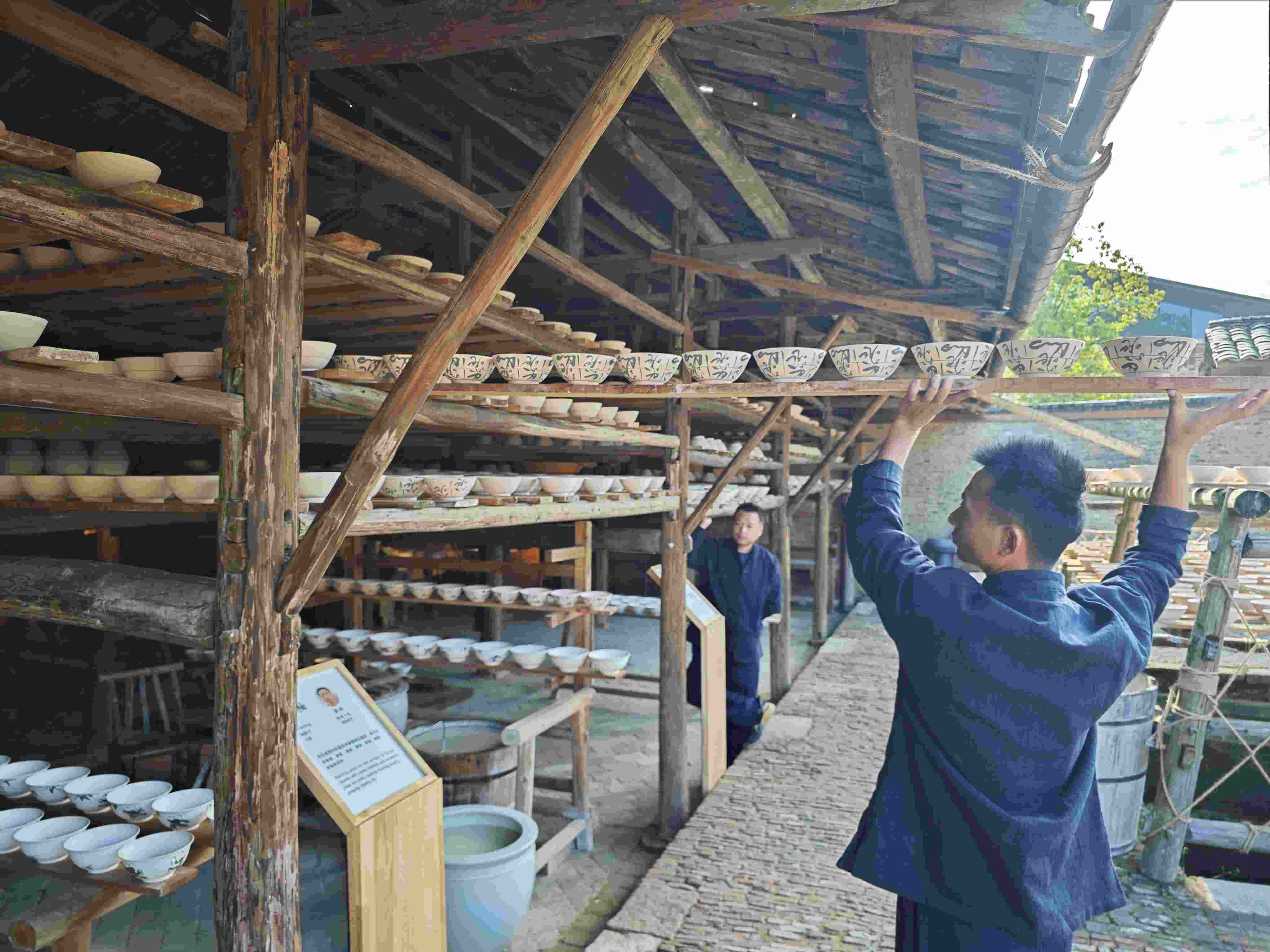 △陶陽里歷史文化街區(qū)里，工匠將陶瓷工藝品放到架上晾干。（總臺央視記者彭漢明拍攝）