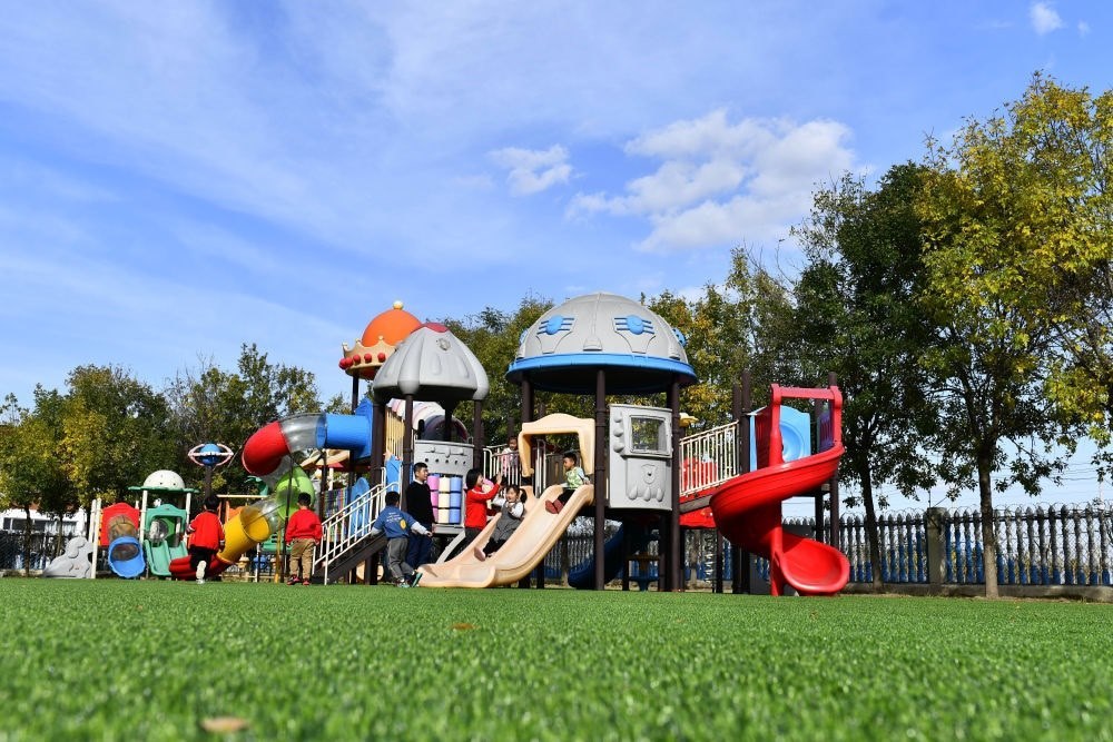 在山東省東營市墾利區(qū)楊廟社區(qū)幼兒園，孩子們在老師的帶領(lǐng)下進行戶外活動（2021年10月19日攝）。新華社記者 郭緒雷 攝
