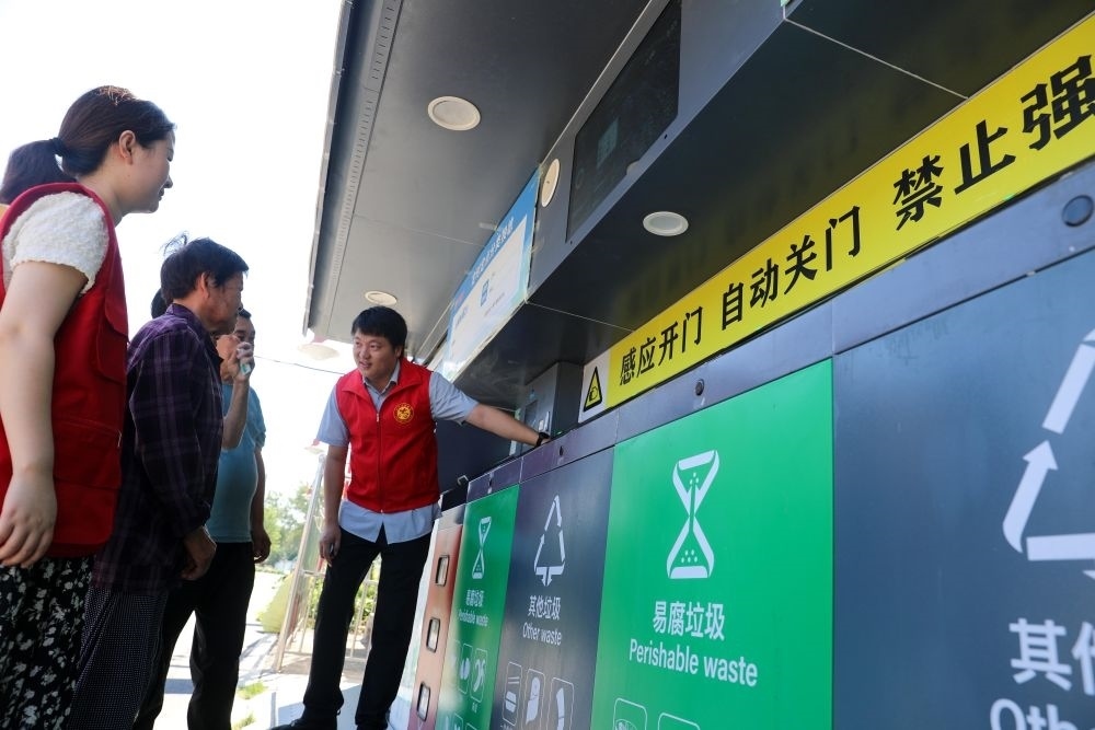 在安徽省合肥市長豐縣莊墓鎮(zhèn)棗林社區(qū)，志愿者指導(dǎo)居民使用智能垃圾分類回收設(shè)備（2023年9月1日攝）。新華社記者 曹力 攝