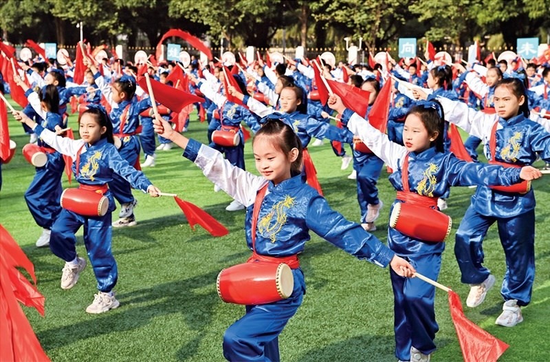 為助推民族地區(qū)基礎(chǔ)教育事業(yè)發(fā)展，廣西重新核定各地中小學(xué)教職工編制，依托全區(qū)編制“周轉(zhuǎn)池”核增事業(yè)編制給各地中小學(xué)，在全面達(dá)到國(guó)家標(biāo)準(zhǔn)的基礎(chǔ)上，進(jìn)一步統(tǒng)籌優(yōu)化和動(dòng)態(tài)調(diào)整各區(qū)域、學(xué)校、學(xué)段間編制資源。圖為2023年11月29日，南寧市濱湖路小學(xué)舉行主題為“逐夢(mèng)新時(shí)代 健體向未來”的體育文化節(jié)，孩子們正在跳腰鼓舞。 新華社記者 周華/攝