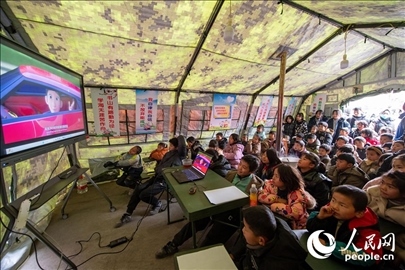 12月22日，在積石山縣大河家鎮(zhèn)大河村安置點，陸軍76集團軍某旅搭建的“臨時學校”內，小朋友正在看動畫片。人民網記者 翁奇羽攝