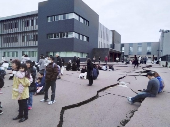  1月1日，在日本石川縣輪島市，人們站在被地震破壞的地面上。新華社/共同社
