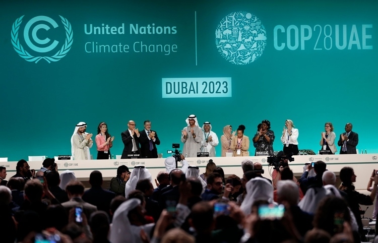 2023年12月13日，在聯(lián)合國氣候變化迪拜大會閉幕全體會議上，COP28主席蘇爾坦·賈比爾宣布達成“阿聯(lián)酋共識”后，參會人員起立鼓掌。新華社記者 王東震 攝