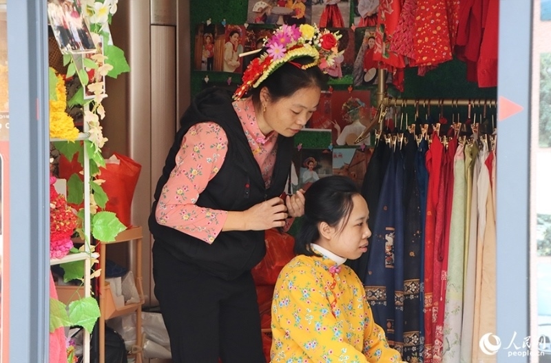 泉州府文廟附近，一名店主正為過路游客梳理頭發(fā)以佩戴“簪花圍”。人民網(wǎng) 黃東儀攝