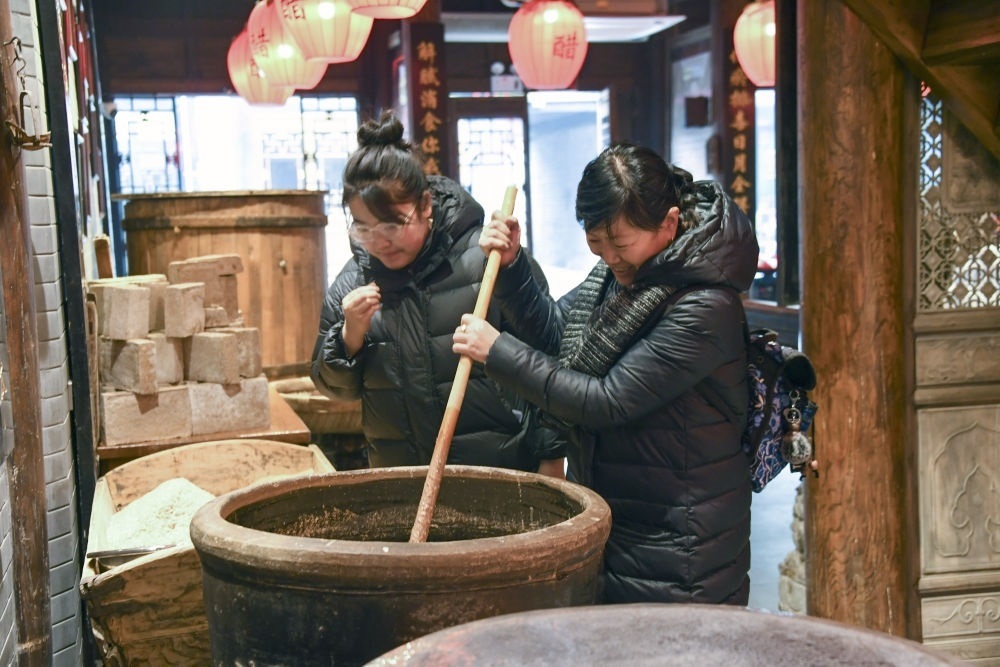 游客在平遙古城東湖老醋坊內(nèi)體驗(yàn)陳醋發(fā)酵打耙（2022年1月28日攝）。新華社發(fā)（梁生仁攝）