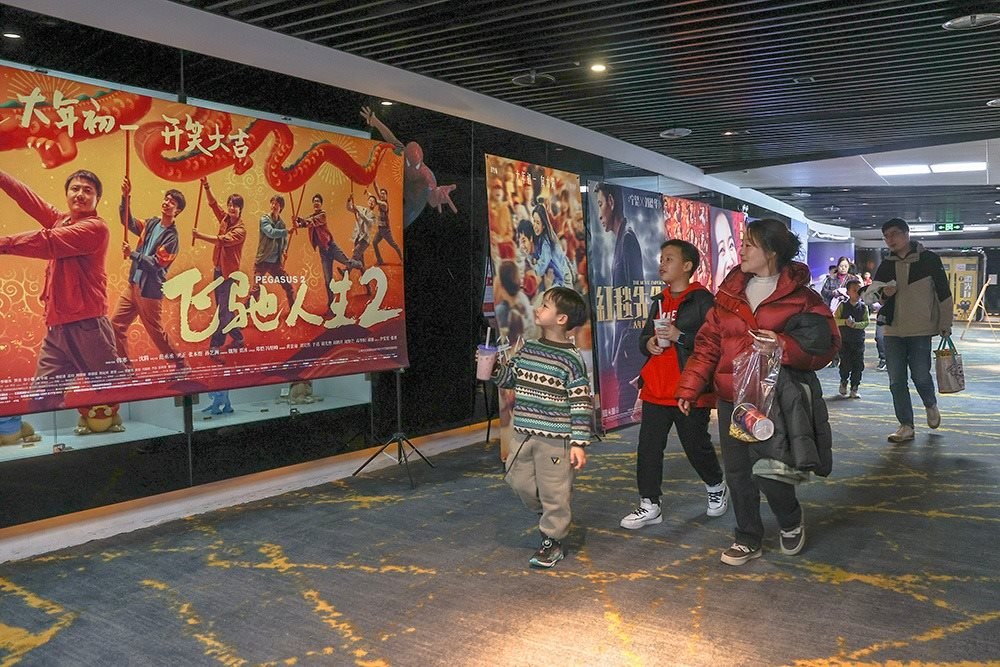△ 2024年2月16日，在江西贛州一家電影院，觀眾從春節(jié)檔電影的宣傳展板前走過(guò)。