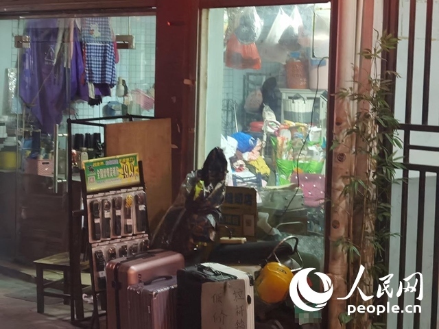 南寧“城中村”一裁縫鋪老板將電線從店內(nèi)拉出為電動(dòng)自行車充電。人民網(wǎng) 覃心攝