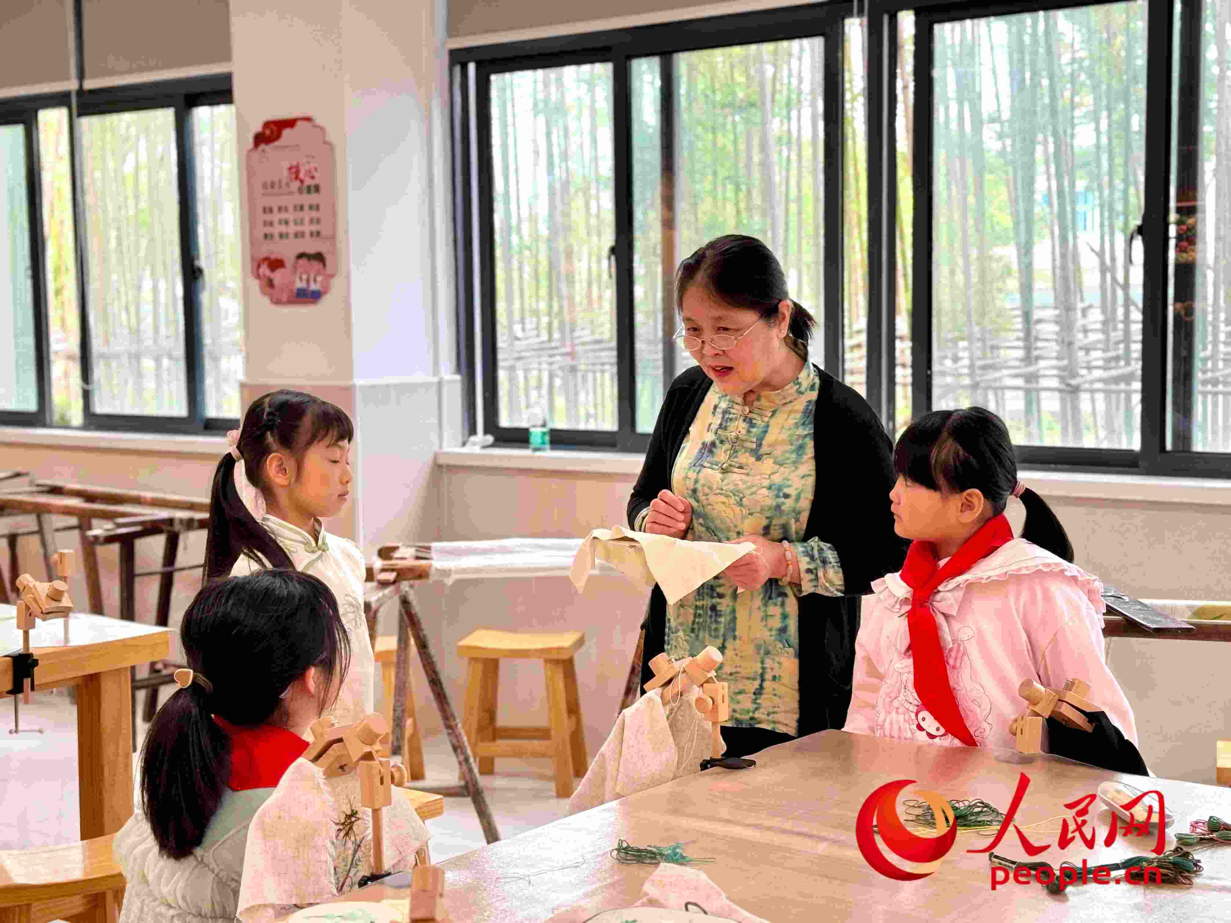 顧建珍（左三）在教孩子們刺繡知識。人民網(wǎng) 周靜圓攝