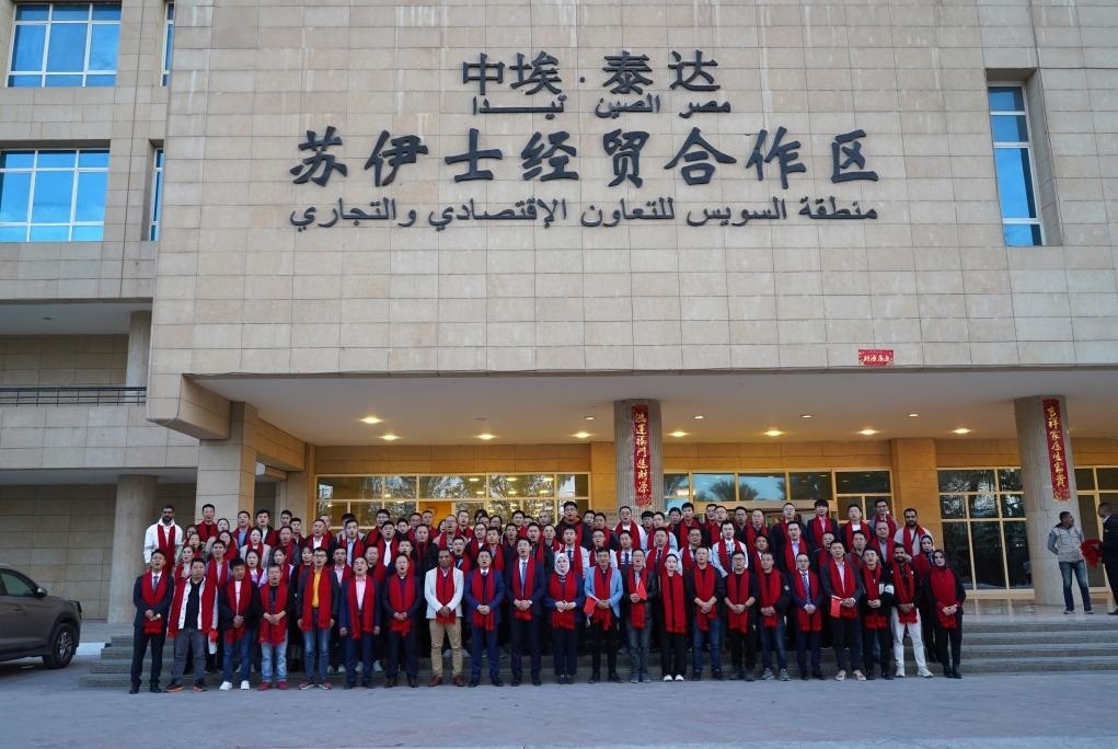2024年2月11日，在位于埃及蘇伊士省的中?！ぬ┻_(dá)蘇伊士經(jīng)貿(mào)合作區(qū)，中埃員工在合作區(qū)辦公大樓前合影拜年。新華社發(fā)（泰達(dá)合作區(qū)供圖）