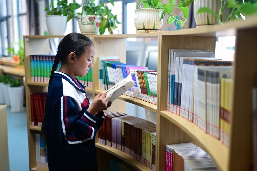 6月18日，果洛西寧民族中學學生尼東拉毛在圖書室看書。