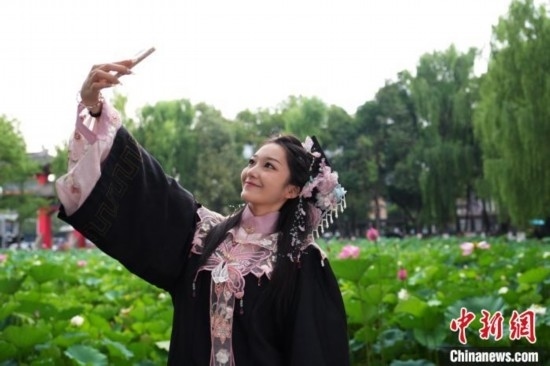 6月19日，時值一年畢業(yè)季，四川大學(xué)望江校區(qū)荷花池里的荷花盛開，成為了畢業(yè)生們的打卡圣地，吸引了眾多畢業(yè)生拍照留念。圖為畢業(yè)生在荷花池邊拍照留念。中新社記者 安源 攝