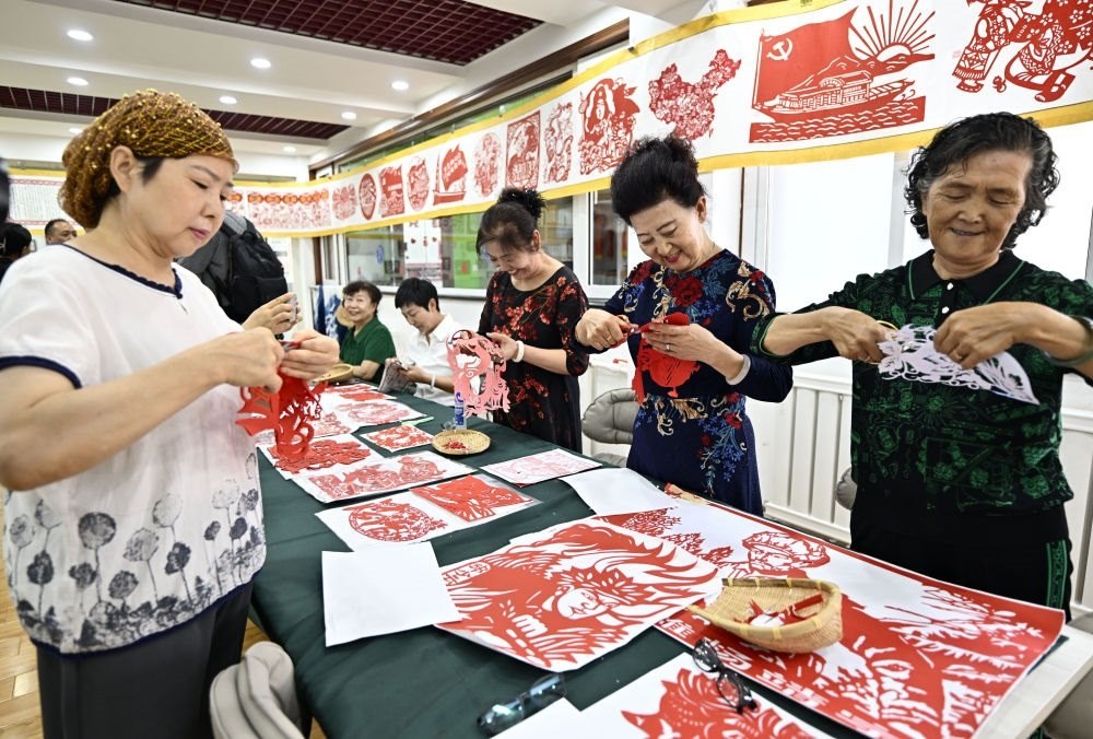 6月19日，長(zhǎng)城花園社區(qū)居民在社區(qū)“才藝堂”制作剪紙。