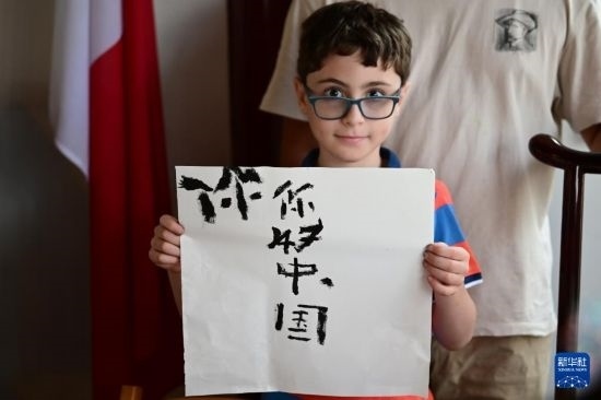 7月4日，在馬耳他桑塔露琪亞市的中國古典園林“靜園”，一名男孩展示他的書法作品。新華社發(fā)（喬納森·博格 攝）