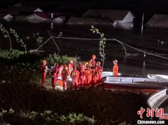  7月6日凌晨3時，在湖南岳陽華容縣團(tuán)洲垸洞庭湖一線堤防，救援人員剛剛完成一次救援任務(wù)，遠(yuǎn)處是被淹的民房。中新社記者 白祖偕 攝
