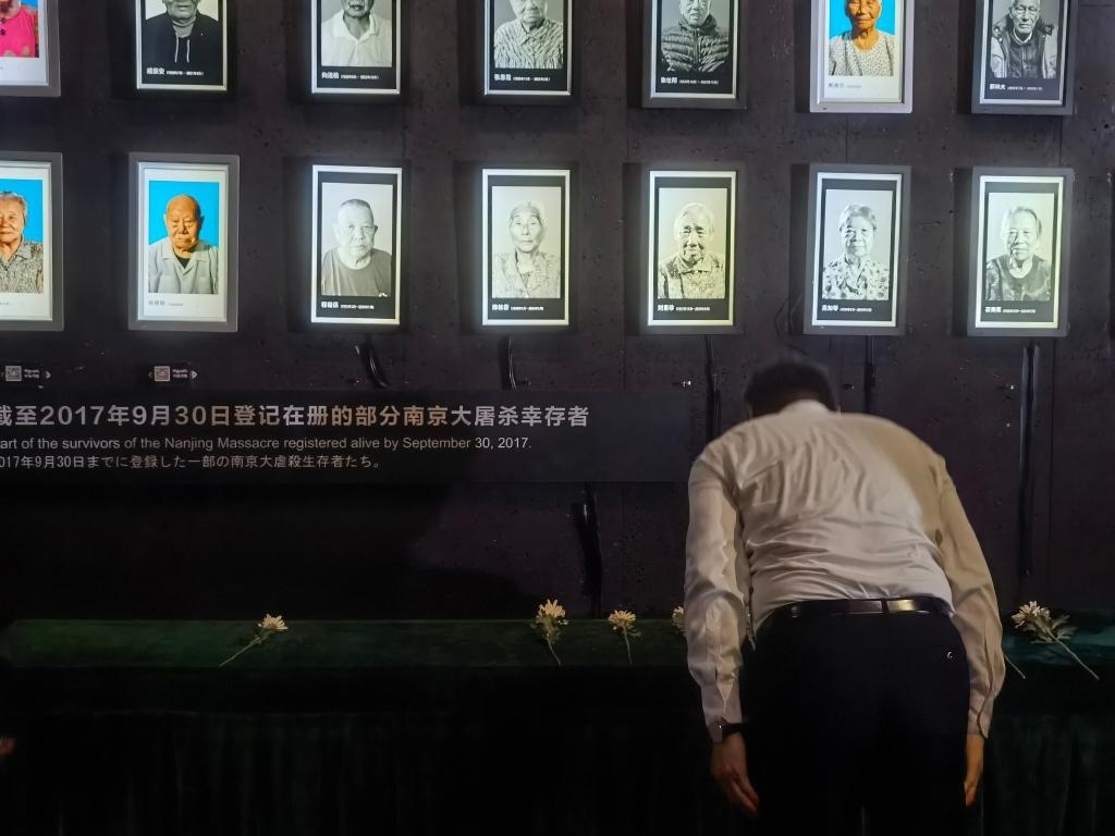 7月18日，人們向離世的南京大屠殺幸存者獻(xiàn)花、鞠躬。新華社記者邱冰清 攝