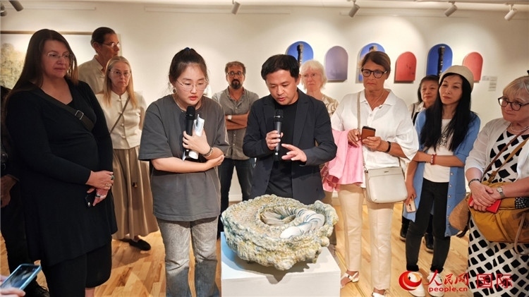 參展人、景德鎮(zhèn)陶瓷大學(xué)設(shè)計藝術(shù)學(xué)院副院長余劍峰（中）向來賓介紹參展作品。人民網(wǎng)記者 殷淼攝