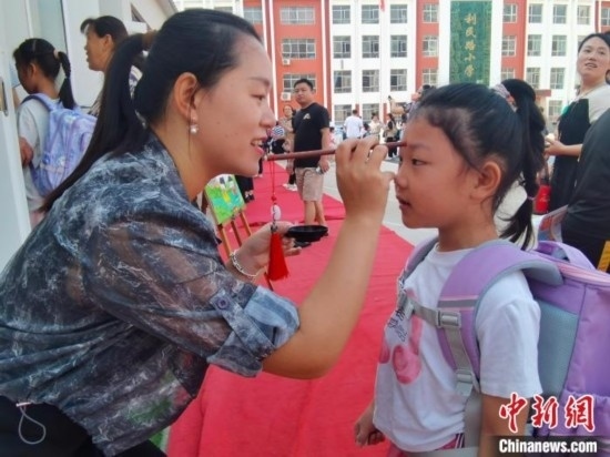 圖為衡水市利民路小學(xué)，老師為學(xué)生點(diǎn)朱砂痣，寓意開(kāi)啟智慧。張松 攝