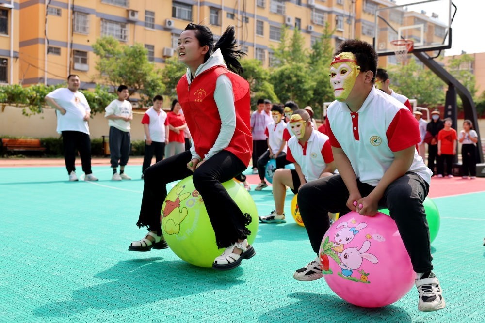 2024年5月17日，在山東省棗莊市市中區(qū)特殊教育中心，青年志愿者與智力障礙學生一起做游戲。新華社發(fā)（孫中喆攝）