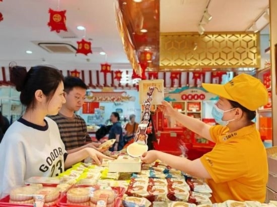 北京稻香村一家門店內(nèi)，售貨員向顧客展示新上市的月餅禮盒。（受訪者供圖）