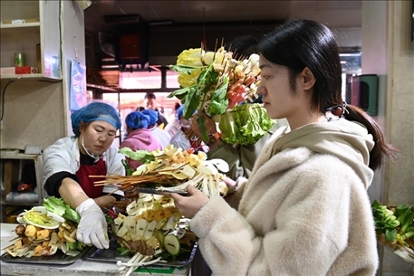 游客挑選好麻辣燙菜品后排隊(duì)等待加工。新華社記者 范培珅 攝