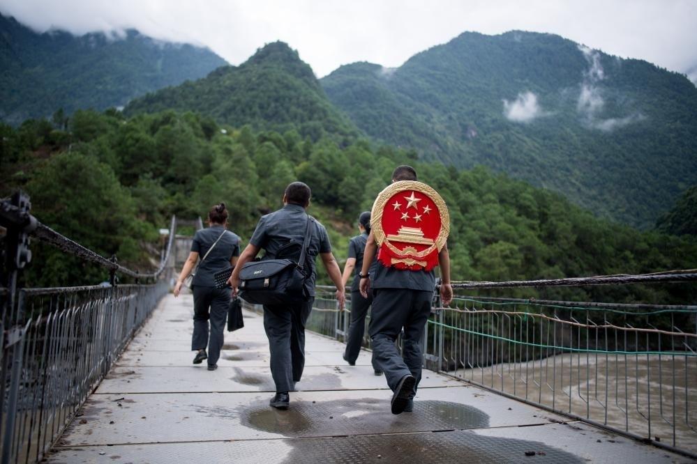 云南省怒江傈僳族自治州貢山縣人民法院法官鄧興背著國徽與同事們跨過怒江（2019年8月30日攝）。怒江高山峽谷眾多，交通不便，為方便群眾、更好地開展法律服務(wù)，背著國徽攀高山、過索橋、躲落石、鉆老林……成為鄧興法官的工作常態(tài)。新華社記者 江文耀 攝