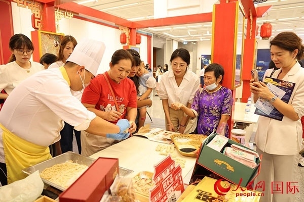 演出前，在天津桂發(fā)祥十八街麻花制作技藝非遺體驗(yàn)展臺(tái)前，泰國(guó)民眾體驗(yàn)天津麻花制作。人民網(wǎng)記者 楊一攝