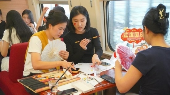 10月1日，旅客們在G1634次列車上給油紙傘作畫。新華社記者周義 攝
