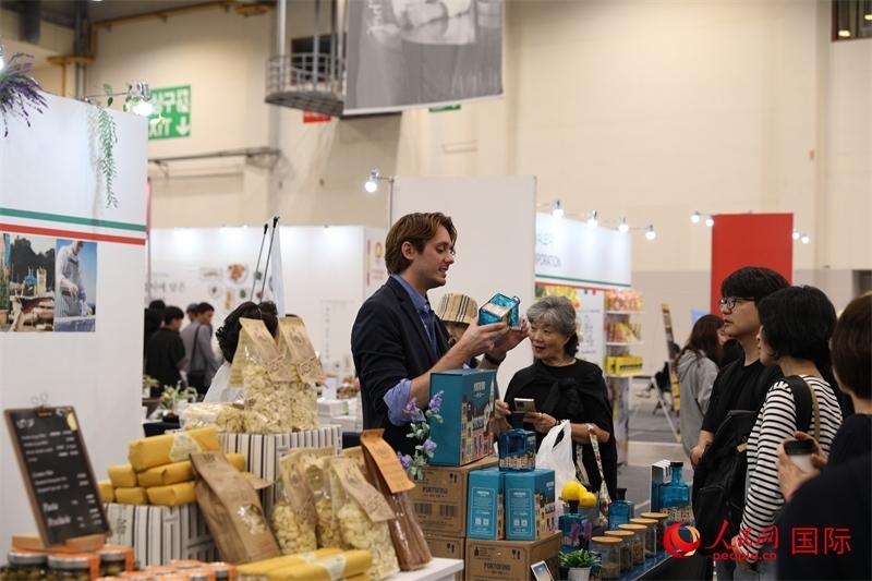 當(dāng)?shù)貢r間10月5日，在第21屆釜山國際美食博覽會上，意大利展商向參觀者們介紹的意大利食品。人民網(wǎng)記者 莽九晨攝
