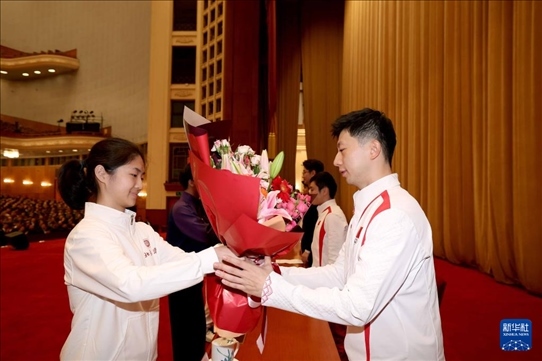 11月15日，一名學(xué)生代表在報(bào)告會(huì)上向乒乓球運(yùn)動(dòng)員馬龍（右）獻(xiàn)花。新華社記者 李明 攝