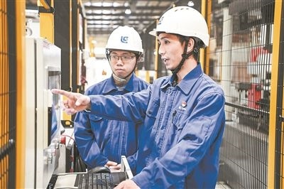 在廣西柳工機(jī)械股份有限公司生產(chǎn)車間內(nèi)，一名高級(jí)技師（右）給徒弟講解數(shù)控設(shè)備操作細(xì)節(jié)。新華社記者 曹祎銘攝