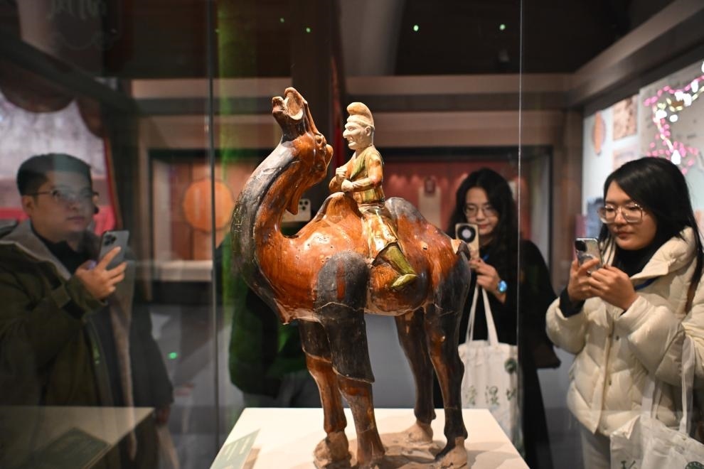 1月15日，觀眾在拍攝“長安三萬里——陜西唐代文物精華展”展出的三彩胡人騎駝俑。（新華社記者 孫凡越 攝）