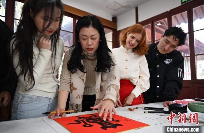 1月20日，西泠印社社員李硯（左二）為外籍留學(xué)生講述蛇年福字貼創(chuàng)作靈感。當(dāng)日，來(lái)自巴西、馬來(lái)西亞、加納、哈薩克斯坦的外籍留學(xué)生在浙江杭州西泠印社體驗(yàn)福貼、春聯(lián)和篆刻，感受古老的中國(guó)傳統(tǒng)文化。中新社記者 王剛 攝